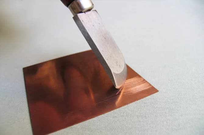 The rocker part way across the plate, the copper behind it dulled where the teeth have passed.